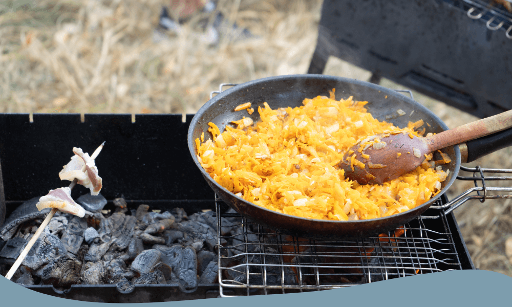 Stekt kål och morötter i en campingstekpanna på grill, idealisk för utomhusmatlagning