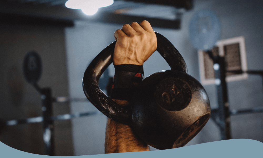 Hand som lyfter en 24 kg kettlebell för styrketräning på gym