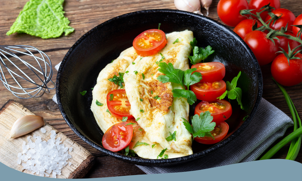 Omelett med tomater och färska örter i gjutjärnspanna, omgiven av ingredienser på ett rustikt träbord