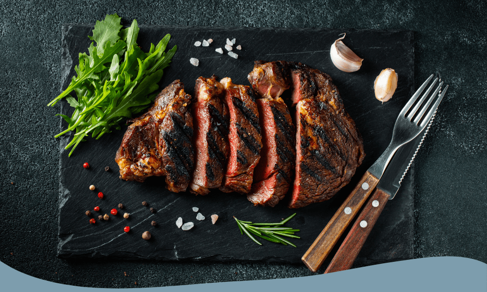 Grillad och skivad ribeye-biff serverad med färska örter, ruccola och kryddor på en skifferplatta