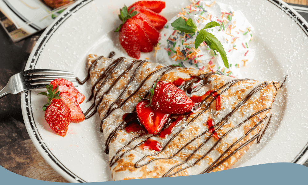 Crepe serverad med jordgubbar, grädde och chokladsås på en elegant tallrik