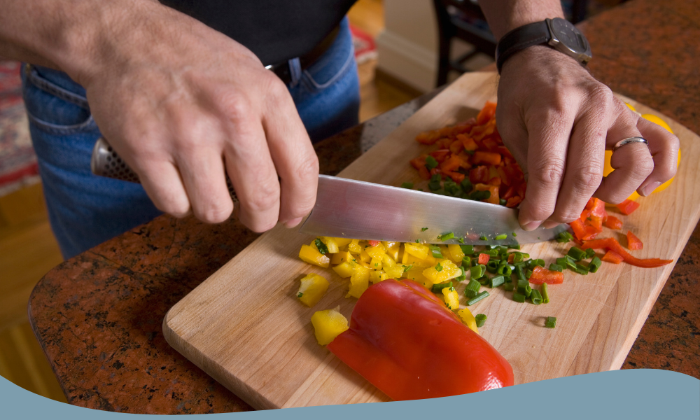 Man hackar grönsaker med en kniv, inklusive paprika och örter för matlagning