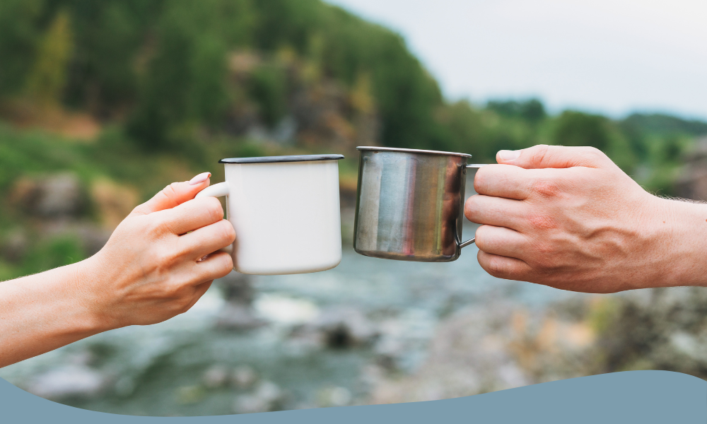 Två händer skålar med metallmuggar – perfekt för kaffe eller te vid camping och friluftsliv.