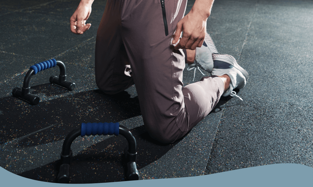 Man redo för armhävningar med push up bars på gymgolv för ökad styrka