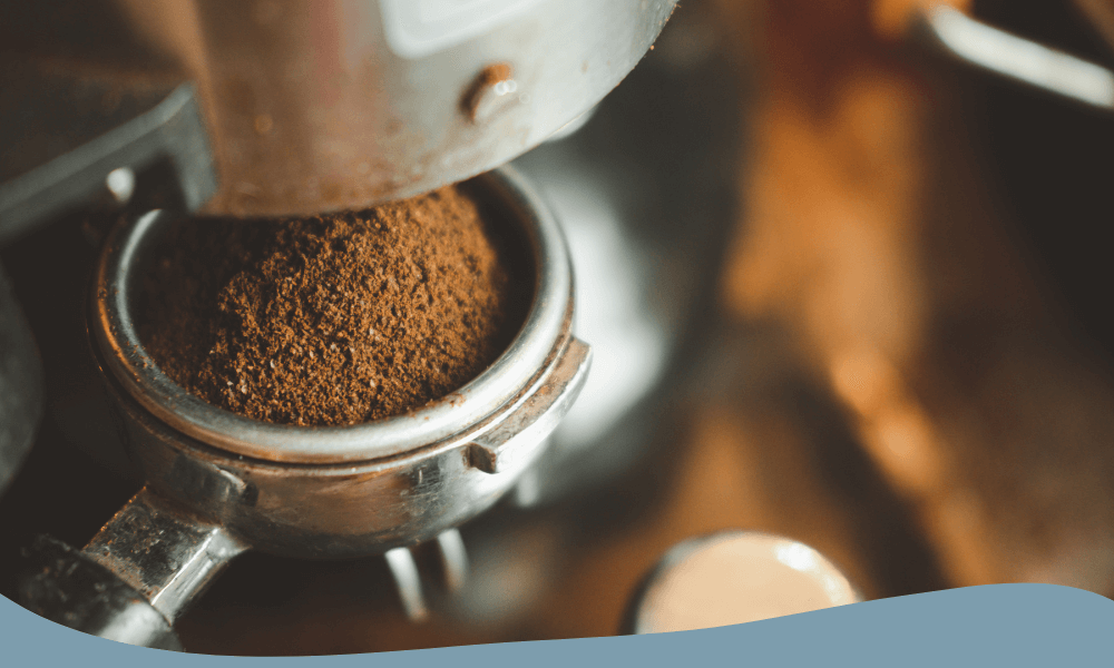 Närbild på nymalet kaffe som doseras i en espressomaskinens filterhållare
