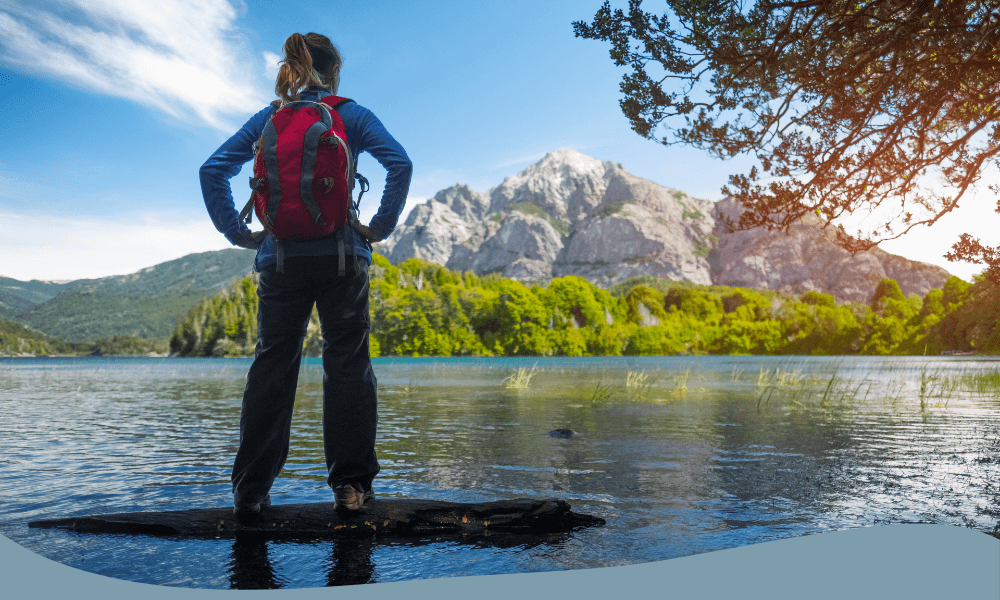 Kvinna med röd friluftsryggsäck vid sjö, perfekt för hiking och äventyr i bergsnatur.
